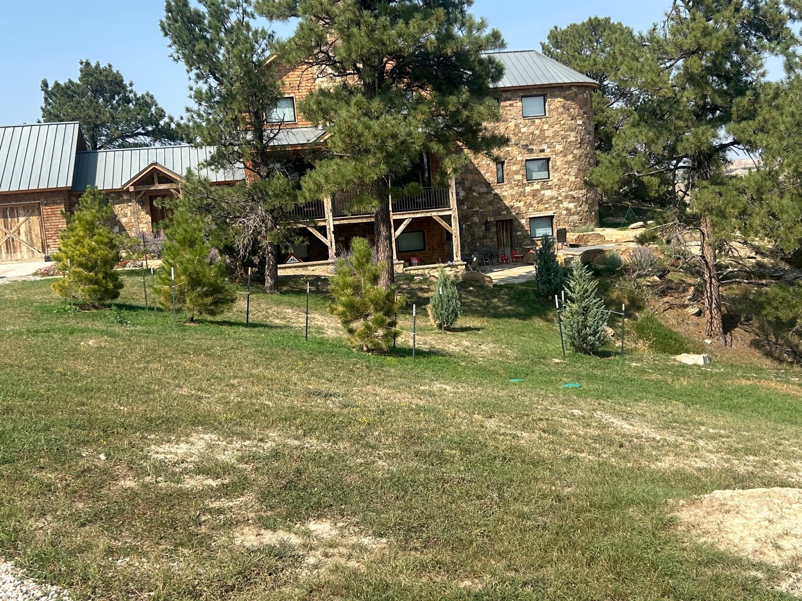 Quarter Circle 7 Ranch — stone lodge with evergreen plantings and native grass