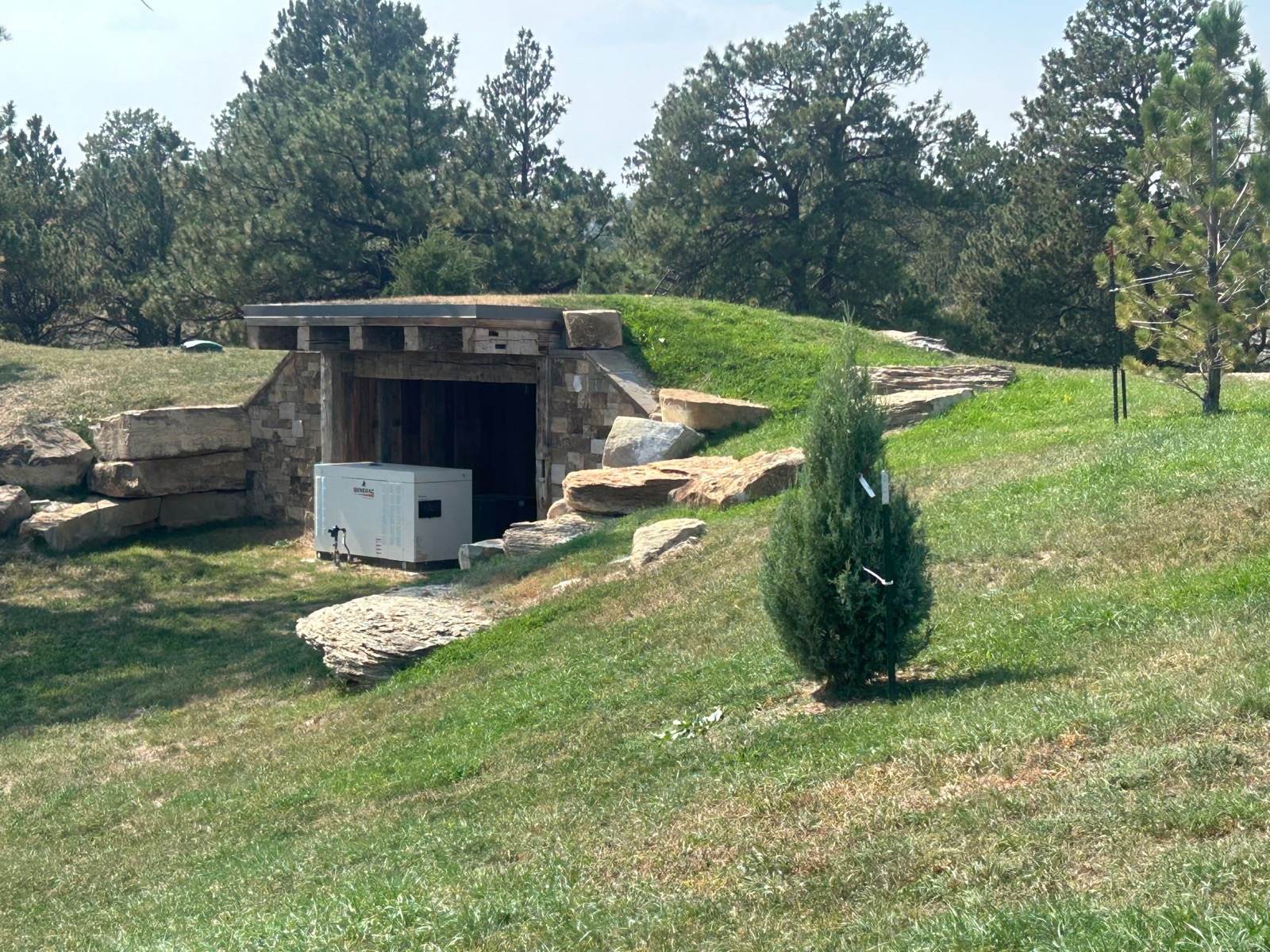 Quarter Circle 7 Ranch — stone storm shelter with native grass and landscaping